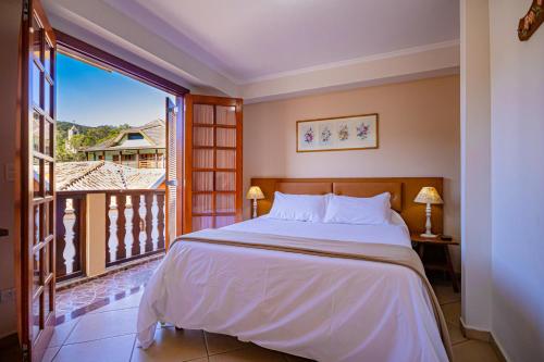 a bedroom with a large bed and a balcony at Pousada Alemã in Santo Antônio do Pinhal
