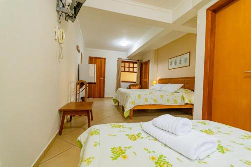 a hotel room with two beds and a table at Pousada Alemã in Santo Antônio do Pinhal