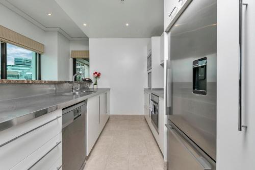 a kitchen with white cabinets and stainless steel appliances at Waterfront Wonder + Cp! in Auckland