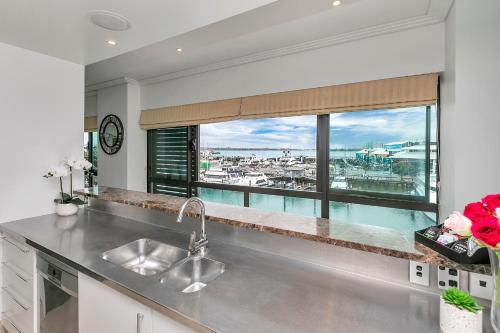 uma cozinha com um lavatório e uma grande janela em Waterfront Wonder + Cp! em Auckland