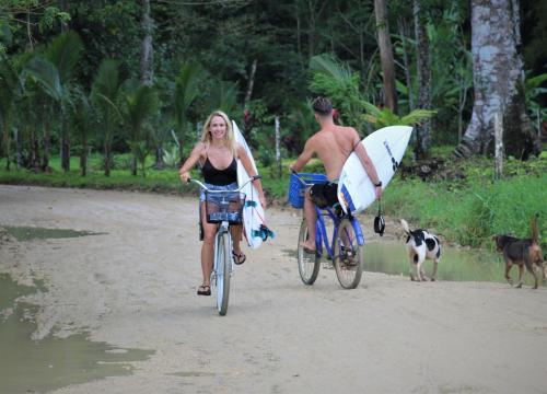 a man and a woman riding bikes on the beach with a surfboard at Jungle Paunch in Bocas del Toro