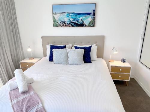 a bedroom with a large white bed with blue pillows at Oracle 28th floor Tower 2 Ocean views! - GC Getaways in Gold Coast