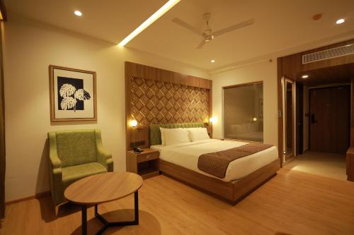 a bedroom with a bed and a chair and a table at MANDARIN SKY in Kannur