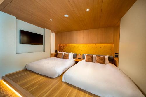 a bedroom with two beds and a tv on the wall at KAYA Kyoto Nijo Castle, BW Signature Collection by Best Western in Kyoto