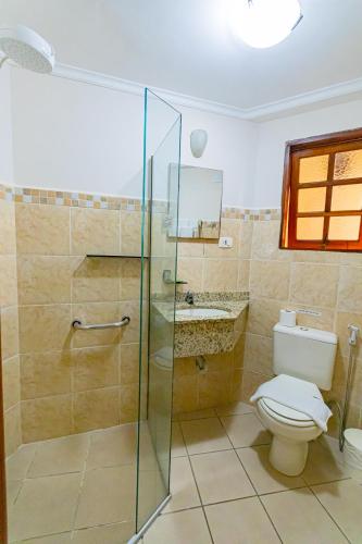 a bathroom with a toilet and a glass shower at Pousada Alemã in Santo Antônio do Pinhal