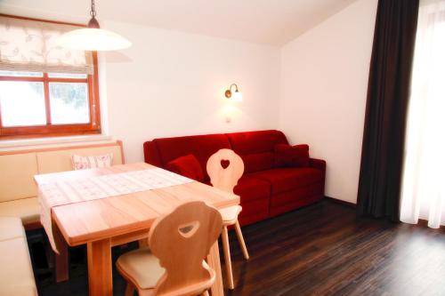 a living room with a table and a red couch at Appartements Stockinger in Grossarl
