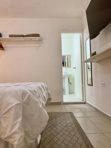 a white bedroom with a bed and a bathroom at Casa Añuiti céntrica ubicación. in San José del Cabo