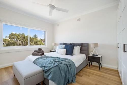 a white bedroom with a large bed and a window at Little Manly Getaway in Sydney