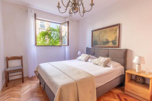 a bedroom with a bed with a chandelier and a chair at Apartments by the sea Podstrana, Split - 15963 in Podstrana