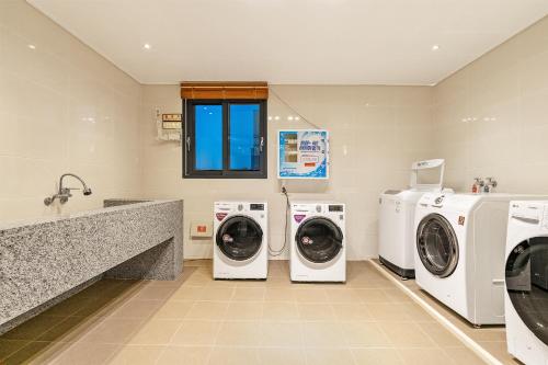 a laundry room with three washing machines and a counter at Pohang A1Hotel Haedo in Pohang