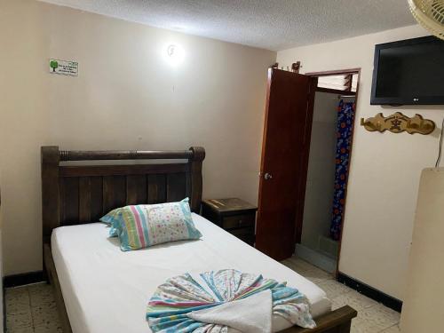 um quarto com uma cama e uma televisão na parede em Hotel calima em Tuluá