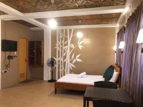 1 dormitorio con 1 cama, 2 sillas y TV en Anahaw Seaside Inn en Bantayan Island