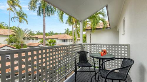 a table and chairs on a balcony with palm trees at 99 Reef Resort Port Douglas in Port Douglas