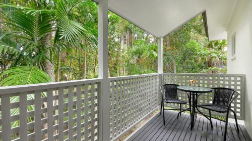 a porch with two chairs and a table on it at 99 Reef Resort Port Douglas in Port Douglas