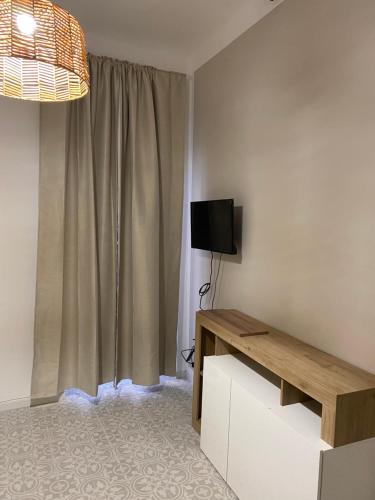 ein Wohnzimmer mit einem TV, einem Tisch und einem Fenster in der Unterkunft Casa la cava in Taranto