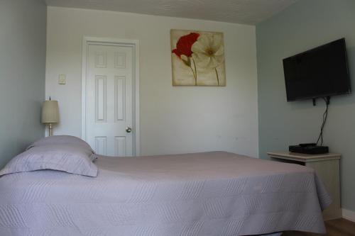 a bedroom with a bed and a flat screen tv at Le Marigot in Vaudreuil-Dorion