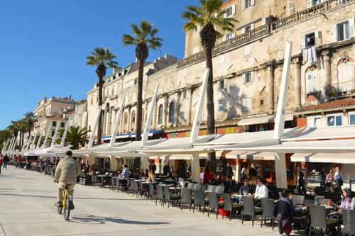 a man riding a bike down a street with tables and chairs at Apartment Vid in Split