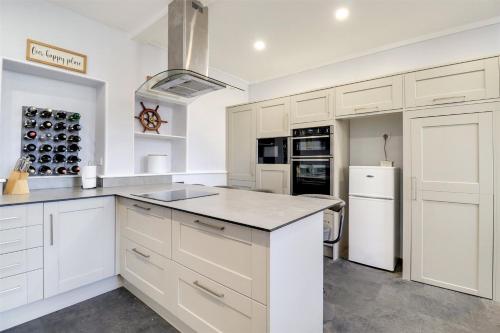 uma cozinha branca com armários brancos e um frigorífico em Wallingbrook Lodge em Chulmleigh