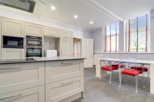 una cocina con armarios blancos y una mesa con sillas rojas en Wallingbrook Lodge en Chulmleigh