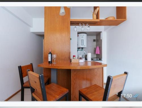 een keuken met een bar met 2 stoelen en een fles wijn bij Departamento en el corazón de Mendoza in Mendoza