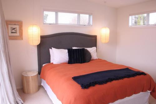 a bedroom with a large orange bed with two windows at Sublime Nooks in Havelock North