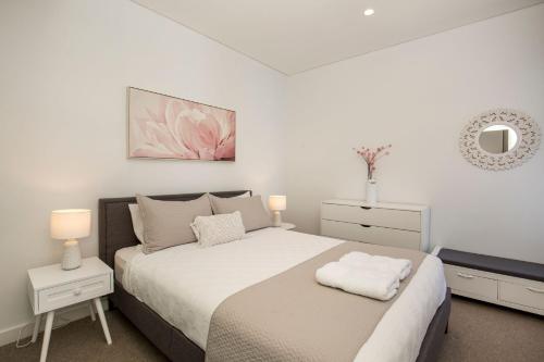 Un dormitorio blanco con una cama y un espejo. en Obsidian Blue Huskisson, en Huskisson