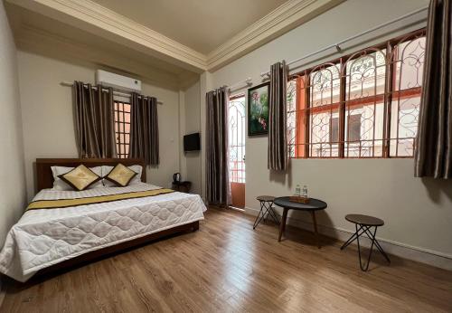 um quarto com uma cama, uma mesa e janelas em MERU em Ho Chi Minh