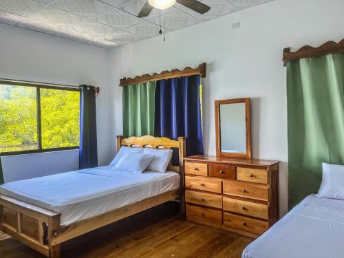 a bedroom with two beds and a dresser and a mirror at Vladi Eco House in Bocas del Toro
