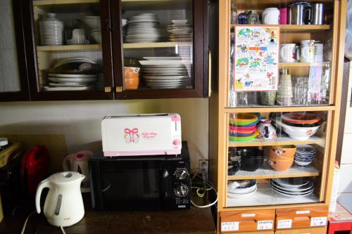 einen Küchenschrank mit Kaffeemaschine und Mikrowelle in der Unterkunft OMOLOSO Hostel　オモロソウ ホステル in Beppu