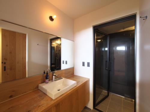 baño con lavabo y espejo grande en ＨＯＴＥＬ ＬＯＣＡＬ ＢＡＳＥ＜宮古島＞, en Isla Miyako