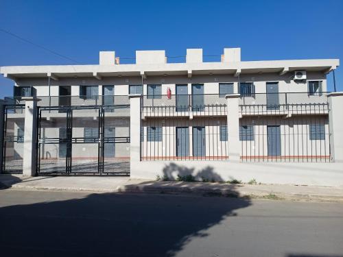 a white building with a gate in front of it at Departamentos Güemes in Chilecito