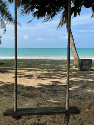 a beach with two palm trees and the ocean at BaanYai Beach Resort Koh Mak in Ko Mak