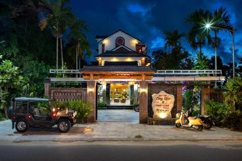 um carrinho de golfe estacionado em frente a um edifício à noite em Citrus Village Villa Hoi An em Hoi An