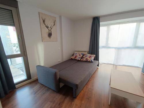 a bedroom with a bed and a couch and windows at Margas Golf Apartment 2 in Sabiñánigo