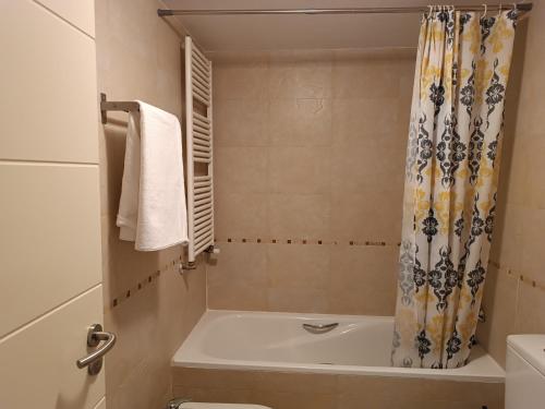 a bathroom with a tub and a shower curtain at Margas Golf Apartment 2 in Sabiñánigo