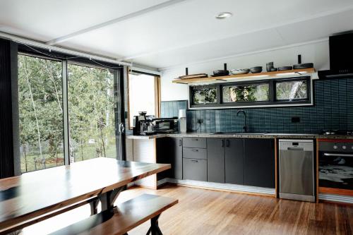eine Küche mit einem Holztisch und einem großen Fenster in der Unterkunft The Artemis Cottage in Fitzroy