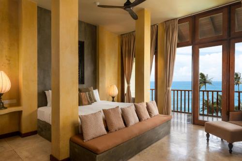 a bedroom with a bed and a balcony with the ocean at Jetwing Lighthouse, A Luxury Reserve in Galle