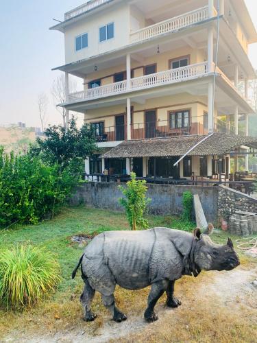 a statue of a rhino walking in front of a house at Hotel Riverside with Swimming pool in Sauraha