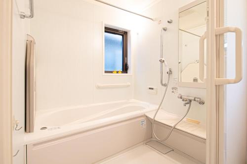 a white bathroom with a tub and a shower at The Wisteria in Osaka