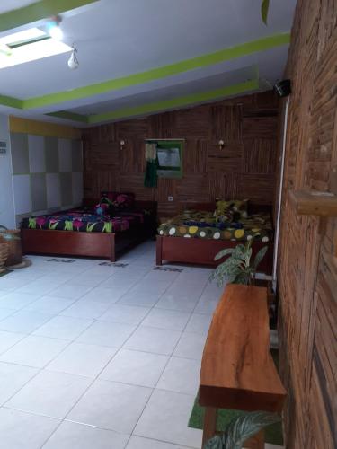 a room with two beds and a bench in it at Budhis Home in Bromo