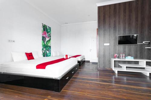 a bedroom with a bed and a tv on a wall at RedDoorz near Grojogan Sewu Tawangmangu in Karanganyar