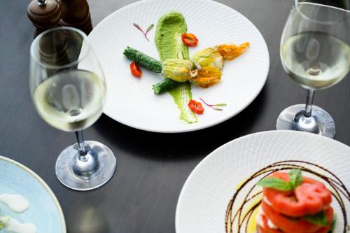 a table with plates of food and glasses of wine at Rendezvous Hotel Perth Scarborough in Perth