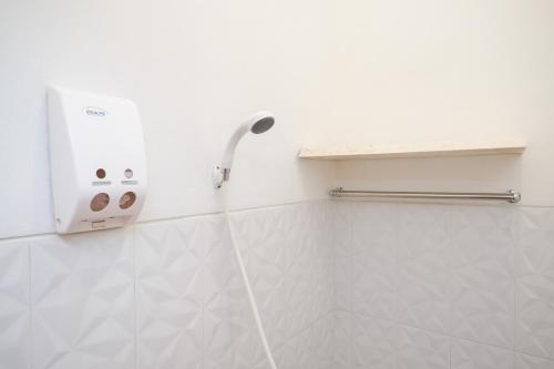 a shower in a bathroom with a white wall at RedDoorz near Grojogan Sewu Tawangmangu in Karanganyar