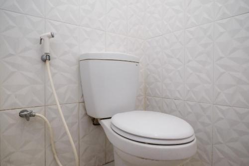 a bathroom with a white toilet with a hose at RedDoorz near Grojogan Sewu Tawangmangu in Karanganyar