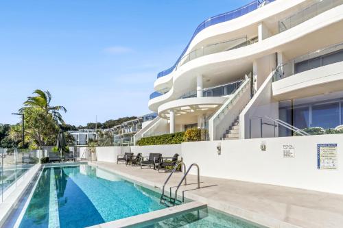 an image of a swimming pool in front of a building at Beachfront luxury, Hastings Street in Noosa Heads