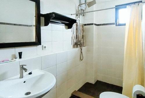 a white bathroom with a sink and a toilet at RedDoorz at Carlton-Martin Hotel Masbate City in Cangbaliguia