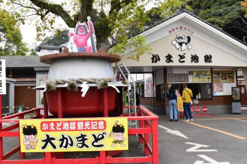 a sign in front of a store with a statue at OMOLOSO Hostel　オモロソウ ホステル in Beppu