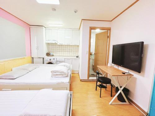a room with two beds and a desk with a television at Sarang Guesthouse Dongdaemun in Seoul