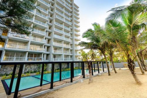 um grande edifício de apartamentos com piscina e palmeiras em MaSa Beach Front Apartment Uswetakeiyawa em Ja-Ela