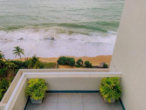 a view of the ocean from a balcony with plants at MaSa Beach Front Apartment Uswetakeiyawa B12 in Ja-Ela